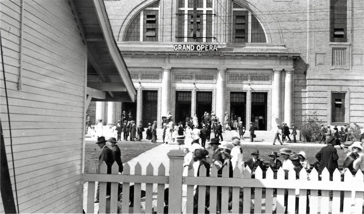 AA PHOTO - TORONTO - EXHIBITION - CNE COLISEUM BUILDING WITH GRAND OPERA SIGN - CROWDS - VIEWED FROM BEHIND PICKET FENCE - NOTE COLISEUM OPENED 1921